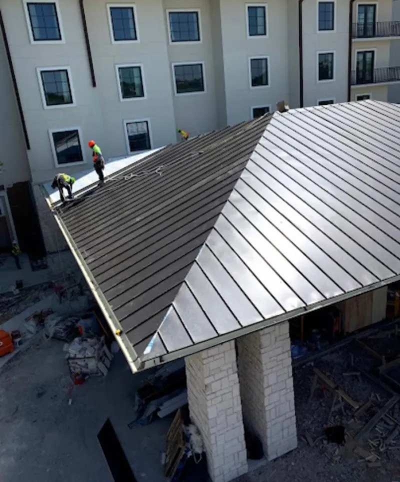 Crew installing standing seam metal roof panels on a commercial project in Westminster